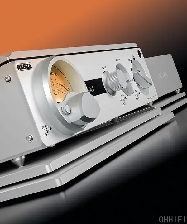 Close-up of Nagra PREAMP II-S preamp on spiked VFS isolation base, Modulometer and volume knob in view, orange backdrop