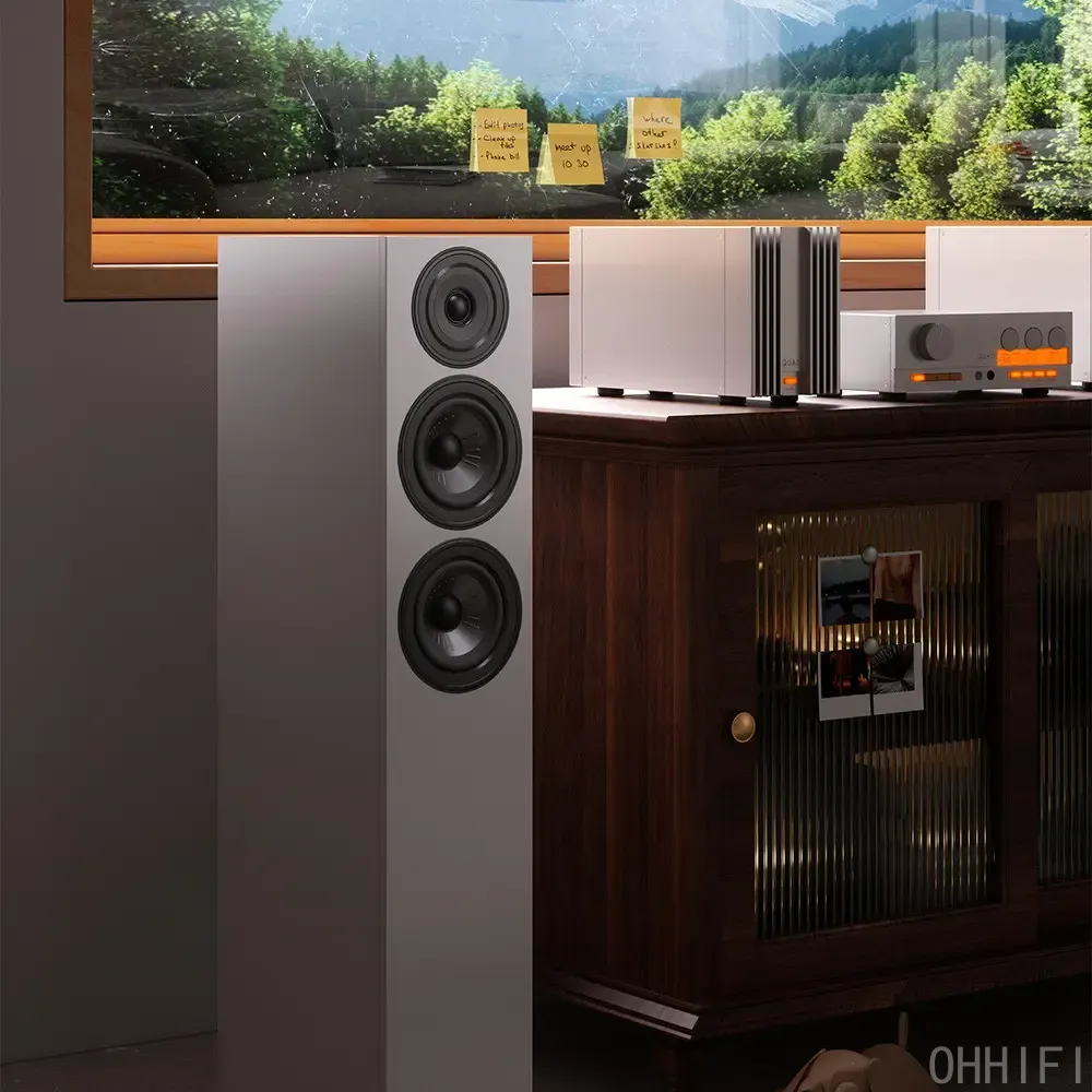 White floorstanding speaker beside a QUAD amplifier and preamp on a walnut sideboard, with a window view behind