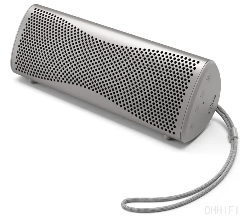 KEF Muo portable Bluetooth speaker in Silver Dusk lying horizontally on a white background, three-quarter view showing the perforated aluminum grille, rear control buttons, end-cap feet and braided wrist strap.