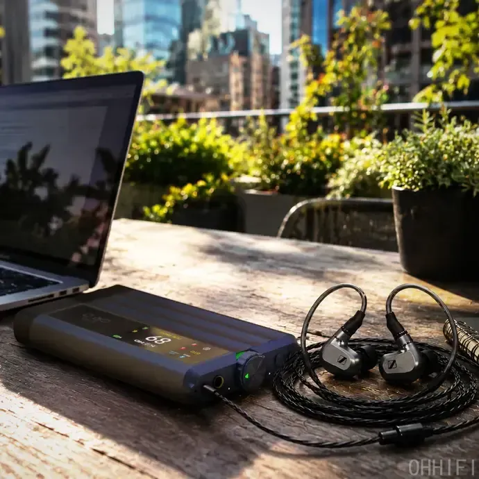 iFi iDSD GR 2 portable DAC/amp on a wooden table, connected to a MacBook and Sennheiser IEMs on a sunny rooftop.