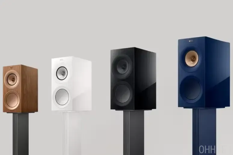 KEF R3 Meta bookshelf speakers lineup in walnut, white, black, and blue finishes, mounted on matching speaker stands